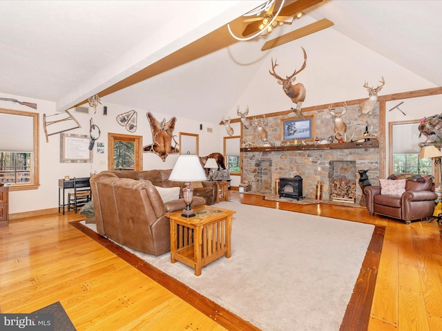 living room with a wood stove, lofted ceiling with beams, and hardwood / wood-style flooring