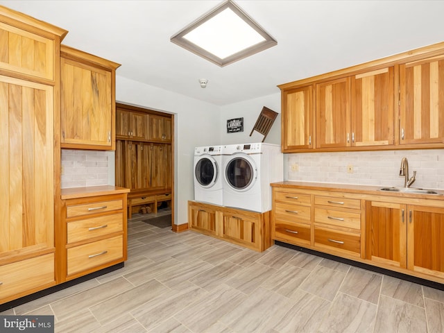 laundry area featuring cabinets, washing machine and dryer, light hardwood / wood-style flooring, and sink