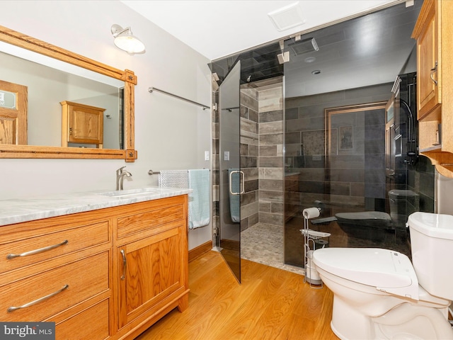 bathroom featuring walk in shower, toilet, vanity, and hardwood / wood-style flooring