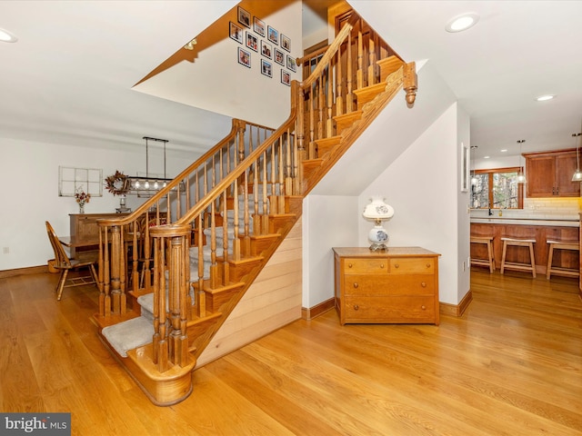 staircase with hardwood / wood-style floors and an inviting chandelier