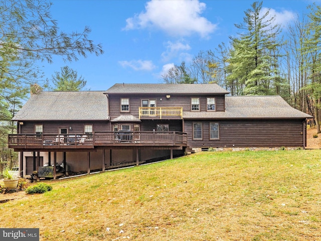 rear view of house featuring a wooden deck and a yard