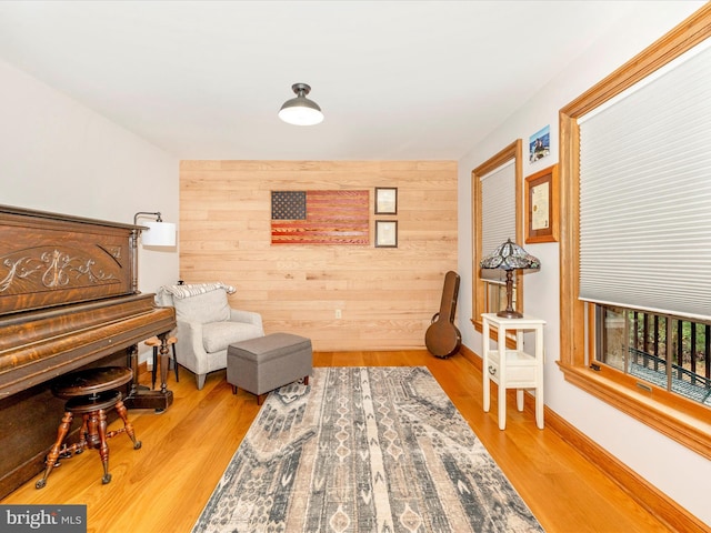 living area featuring light wood-type flooring and wooden walls