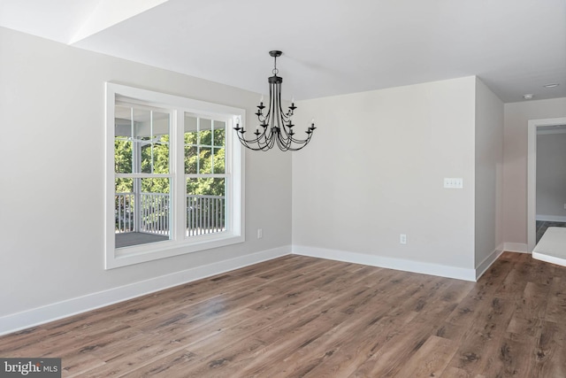 unfurnished dining area with a notable chandelier and dark hardwood / wood-style flooring