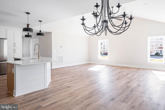 unfurnished dining area featuring an inviting chandelier, vaulted ceiling, and light wood-type flooring