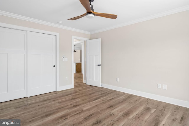 unfurnished bedroom with hardwood / wood-style flooring, ceiling fan, ornamental molding, and a closet