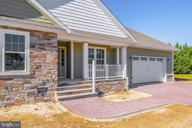 view of exterior entry featuring a porch and a garage