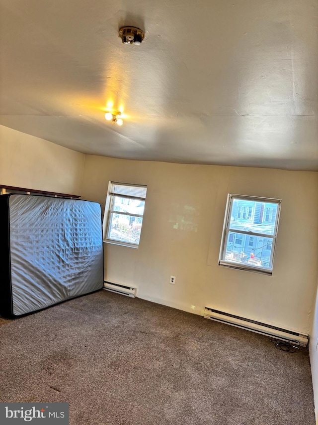 unfurnished bedroom with carpet and a baseboard heating unit