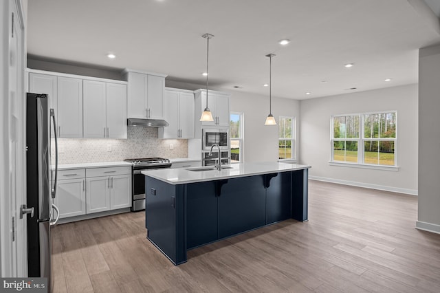 kitchen featuring pendant lighting, white cabinets, a center island with sink, and stainless steel appliances