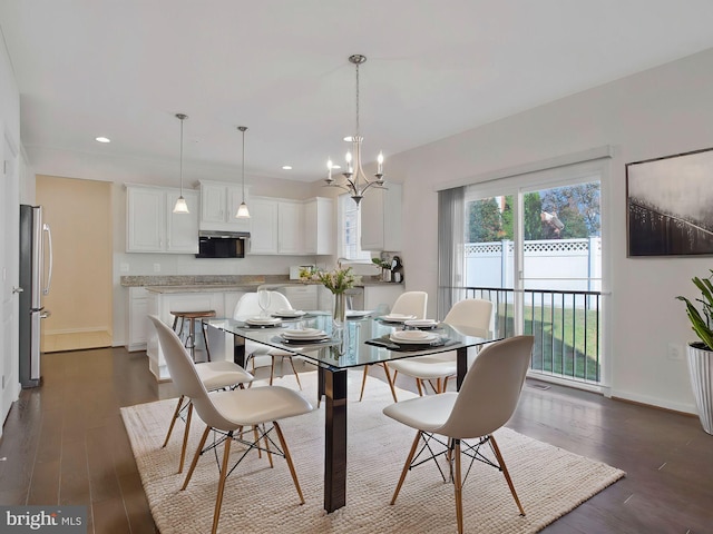 dining area with dark hardwood / wood-style flooring and an inviting chandelier