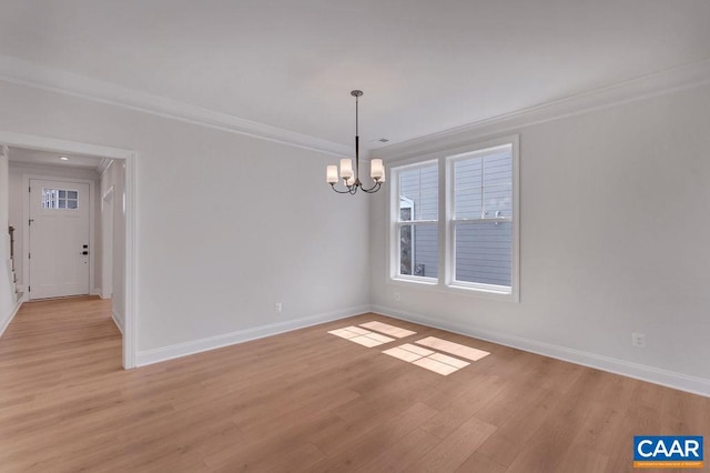 unfurnished room with ornamental molding, light wood-type flooring, and a chandelier