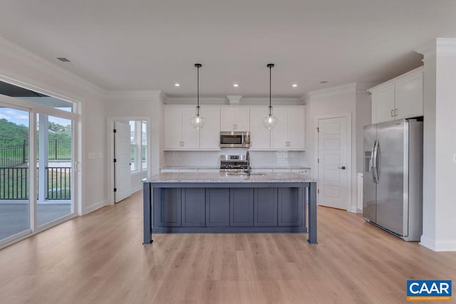 kitchen with white cabinets, a center island with sink, decorative light fixtures, and appliances with stainless steel finishes