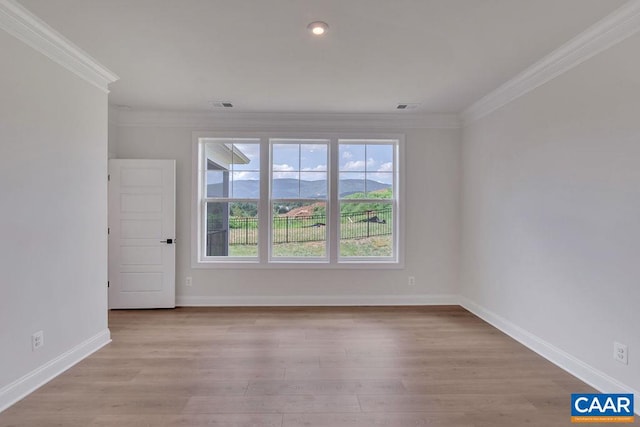 empty room with ornamental molding, a mountain view, and light hardwood / wood-style flooring