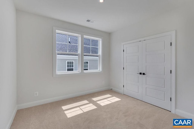 unfurnished bedroom featuring light colored carpet and a closet