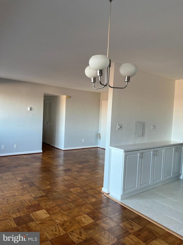 tiled spare room with a notable chandelier