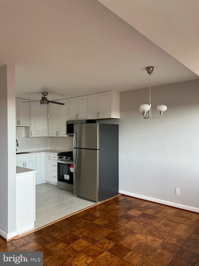 kitchen featuring tasteful backsplash, stainless steel appliances, an inviting chandelier, white cabinetry, and hanging light fixtures