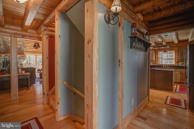 corridor with light hardwood / wood-style flooring, beamed ceiling, and wood ceiling