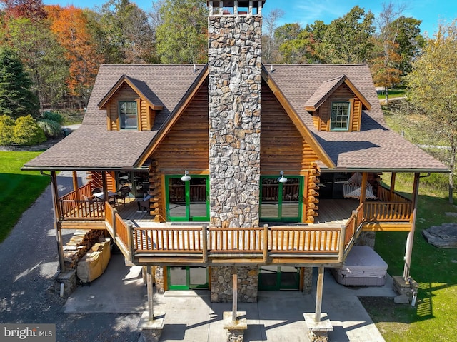 rear view of property featuring a wooden deck and a lawn