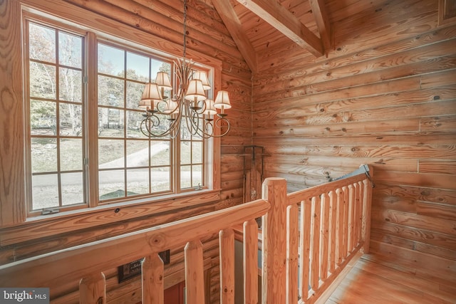 hall with rustic walls, vaulted ceiling with beams, a notable chandelier, and a healthy amount of sunlight