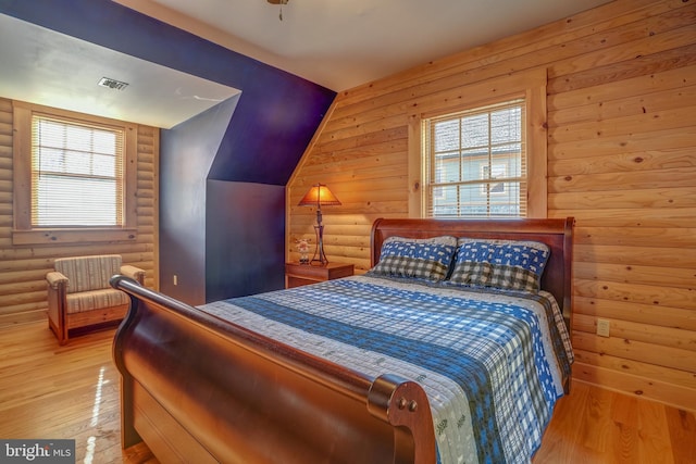 bedroom featuring light wood-type flooring and log walls