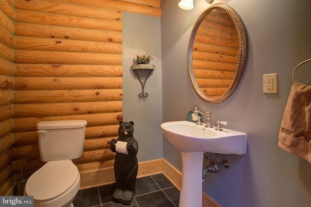 bathroom with toilet, rustic walls, and tile patterned floors