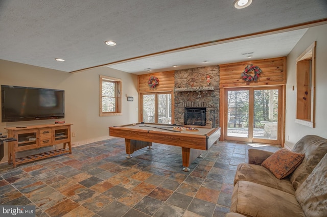 rec room with a stone fireplace, pool table, and a textured ceiling