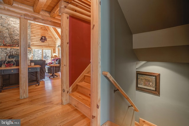 stairway featuring vaulted ceiling with beams, wood-type flooring, log walls, and wood ceiling