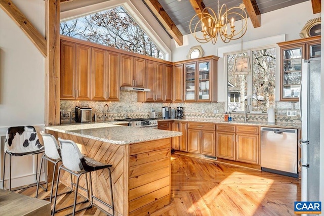 kitchen with kitchen peninsula, tasteful backsplash, pendant lighting, lofted ceiling with beams, and appliances with stainless steel finishes