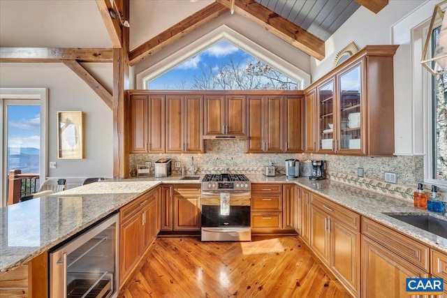 kitchen with wine cooler, light stone countertops, tasteful backsplash, and stainless steel gas range oven