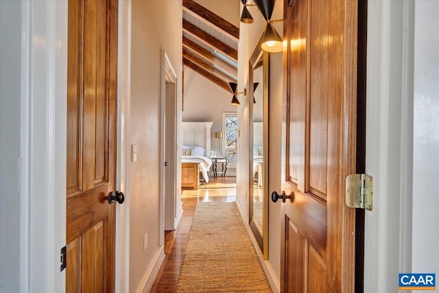 corridor with light hardwood / wood-style floors and lofted ceiling with beams