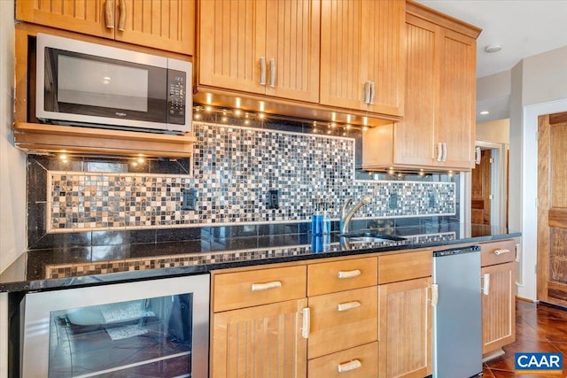 kitchen featuring sink, beverage cooler, dark stone countertops, and backsplash