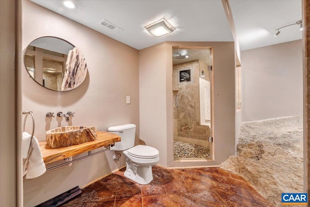 bathroom featuring a shower with door and toilet