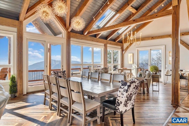 sunroom with a mountain view, a chandelier, lofted ceiling with skylight, and wood ceiling