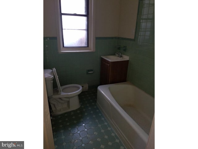 bathroom with tile walls, tile patterned flooring, a bath, and toilet