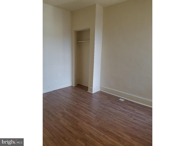 unfurnished bedroom with dark wood-type flooring, a closet, and a textured ceiling