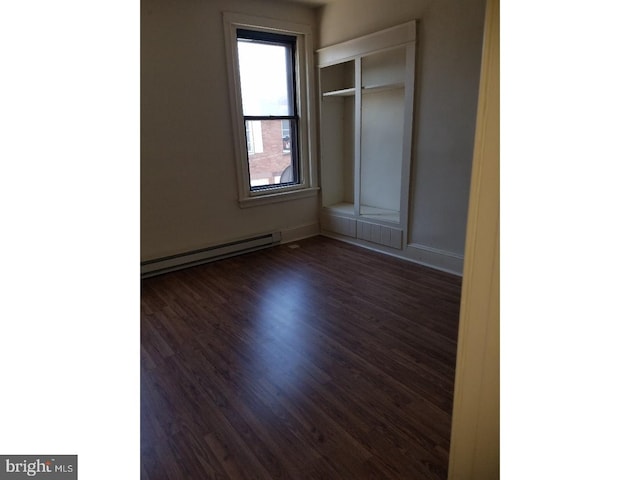 empty room with dark wood-type flooring and baseboard heating