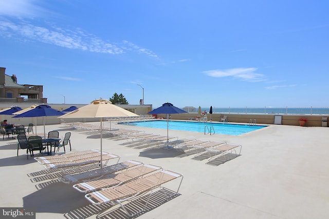 view of swimming pool with a water view and a patio area