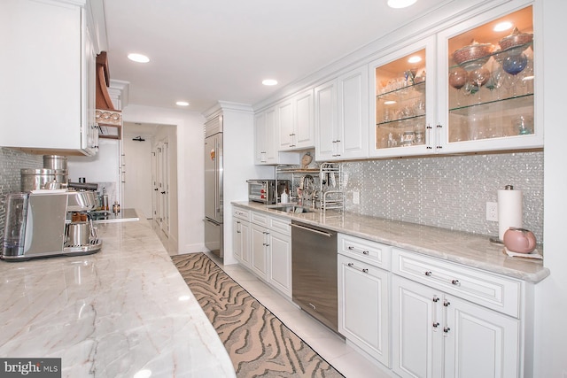 kitchen featuring stainless steel appliances, light stone countertops, white cabinetry, and premium range hood