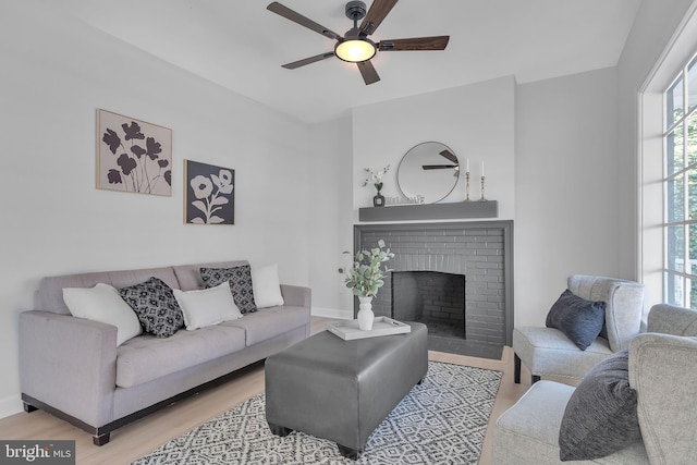 living room featuring a fireplace, ceiling fan, and light hardwood / wood-style flooring