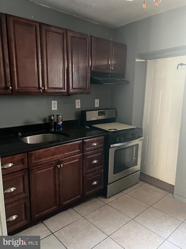 kitchen featuring dark brown cabinets, stainless steel electric range oven, light tile patterned floors, and sink