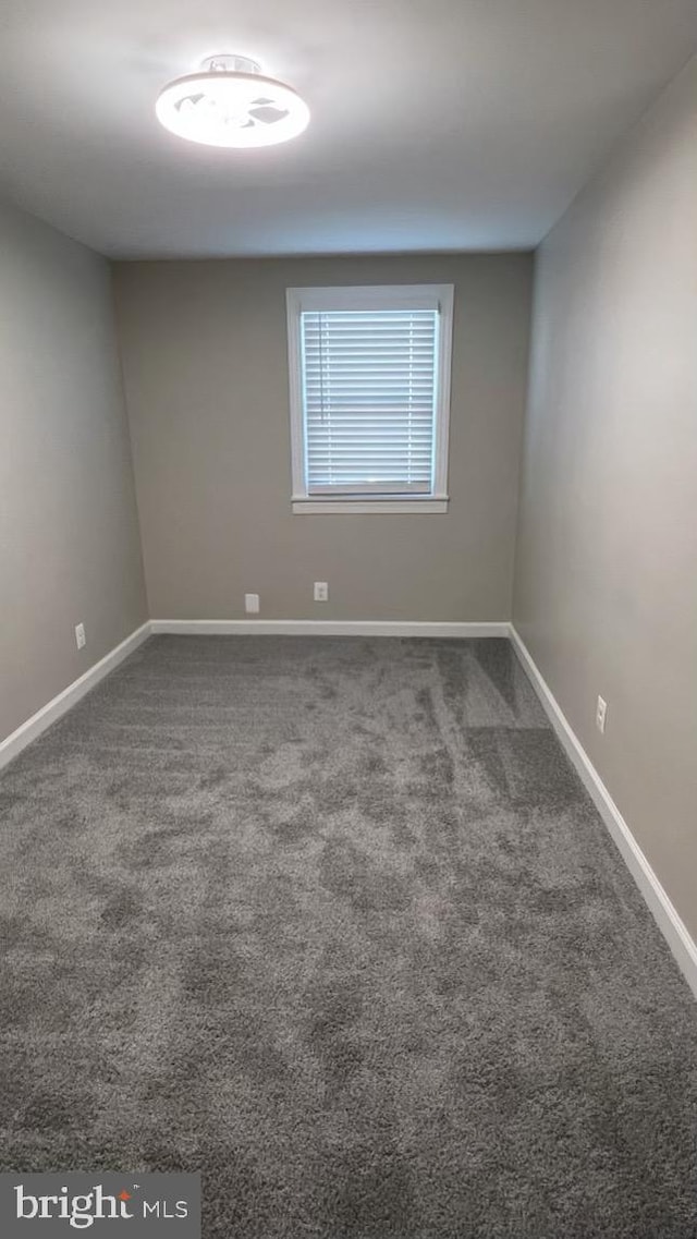 spare room with dark carpet