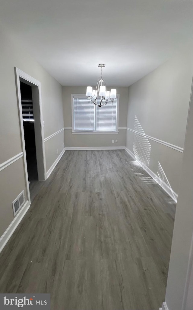 unfurnished dining area featuring dark hardwood / wood-style floors and a chandelier