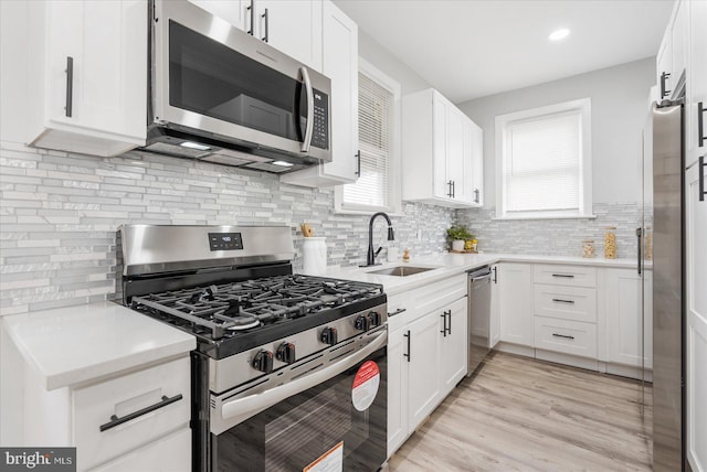 kitchen with a wealth of natural light, sink, white cabinets, and appliances with stainless steel finishes