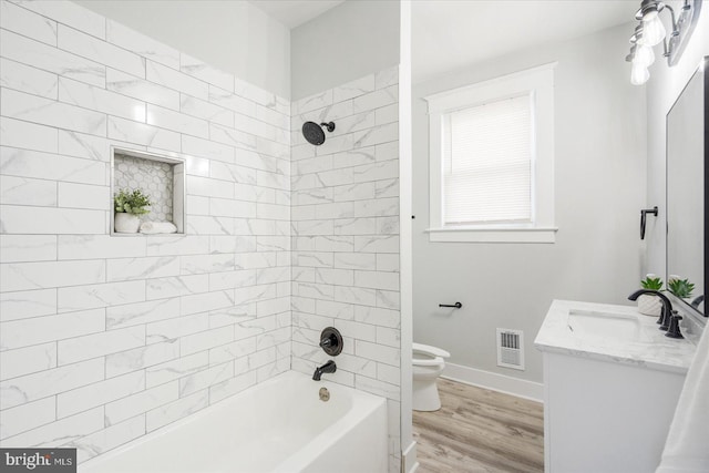 full bathroom with vanity, wood-type flooring, tiled shower / bath combo, and toilet