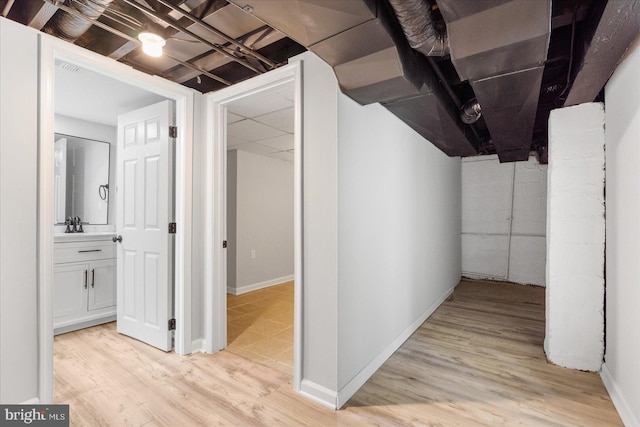 basement featuring light hardwood / wood-style flooring and sink