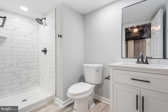 bathroom with tiled shower, wood-type flooring, vanity, and toilet