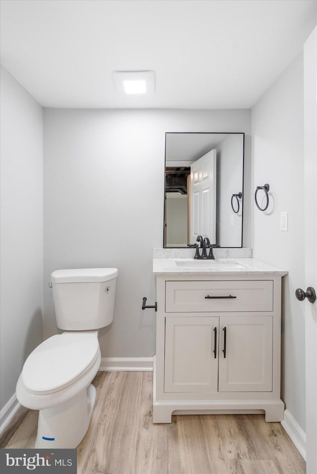 bathroom with toilet, vanity, and hardwood / wood-style flooring