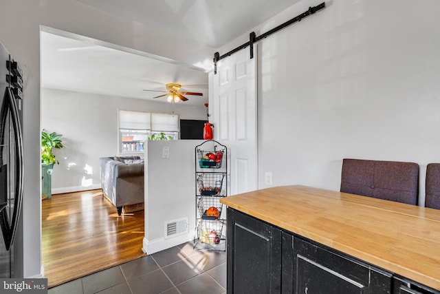 kitchen with a barn door, refrigerator, ceiling fan, and dark wood-type flooring