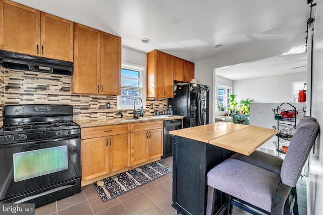 kitchen with exhaust hood, black appliances, dark tile patterned flooring, sink, and decorative backsplash