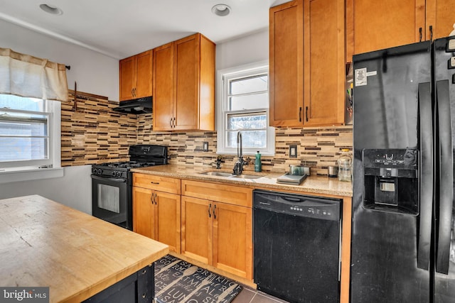 kitchen featuring sink, tile patterned flooring, ventilation hood, decorative backsplash, and black appliances