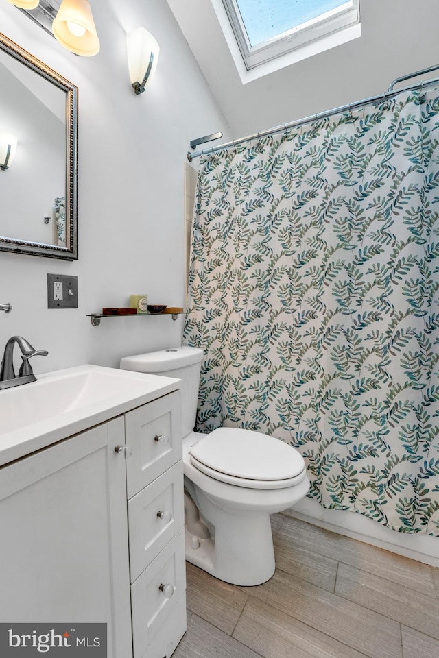 bathroom with a skylight, vanity, wood-type flooring, toilet, and curtained shower